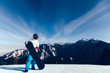 Kış zirvesinde snowboard yapan bir snowboardcu.