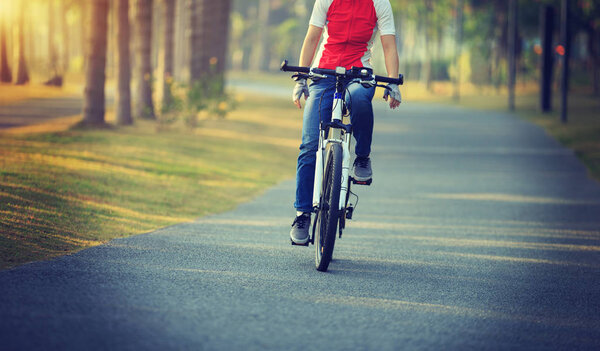 женщина-велосипедистка на велосипеде в тропическом парке
