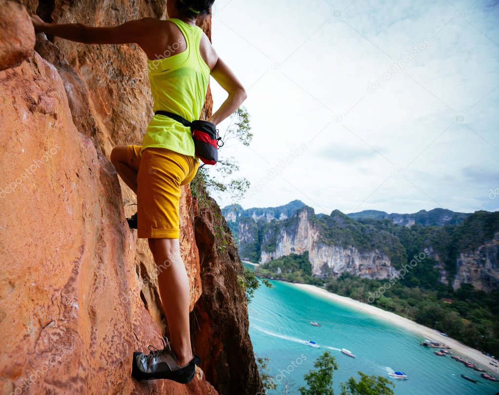 woman rock climber climbing on seaside cliff