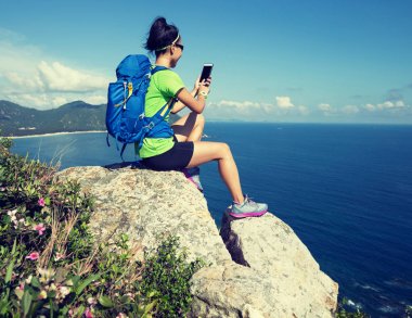 başarılı kadın backpacker Smartphone sahil dağ cliff üzerinde kullanma  