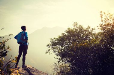 kadın backpacker dağ üst uçurumun kenarında manzaraya bakarak