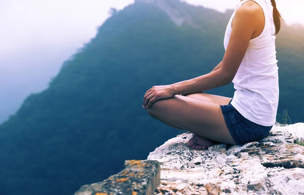 One woman practicing yoga at mountain peak