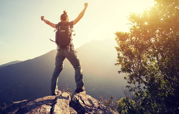 successful hiker with arms outstretched on sunrise mountain top