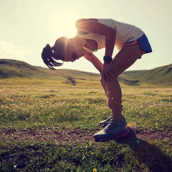 年轻的健身女跑步运动员系鞋带日落草原的小路上 — 图库照片