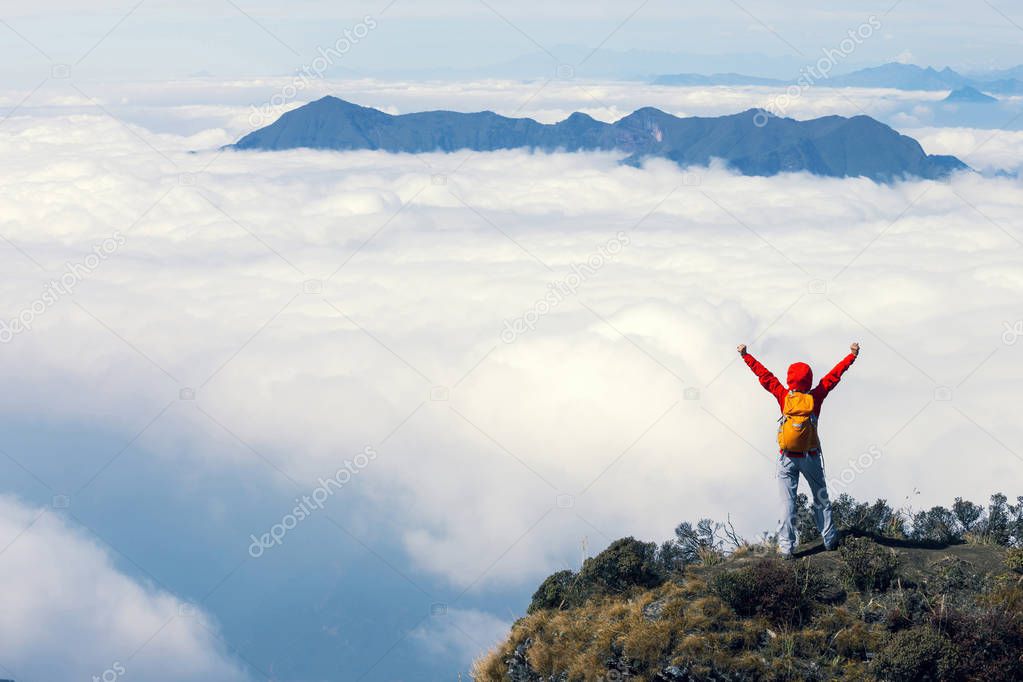 successful hiker with arms outstretched on mountain  