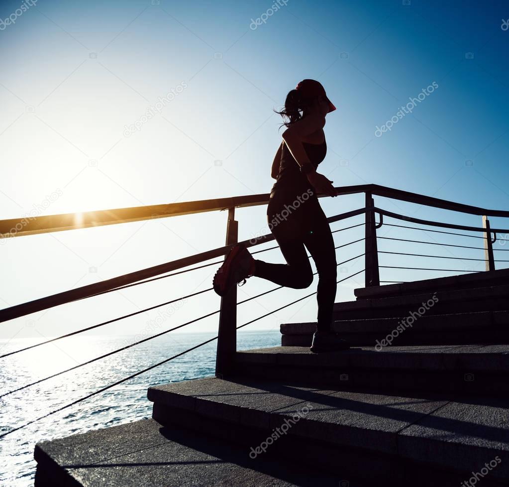sporty fitness female runner running upstairs on coast trail
