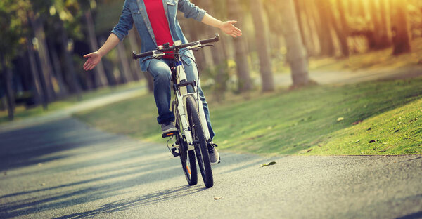 счастливая женщина велосипедистка на велосипеде в весеннем тропическом парке
