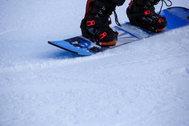 Bir snowboardcu kış dağlarında snowboard yapıyor.