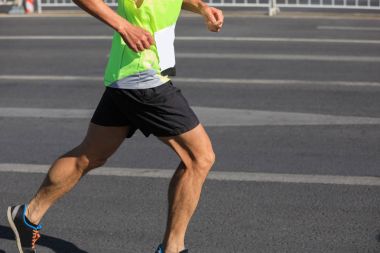 Şehir yolunda koşan maraton koşucusu bacakları