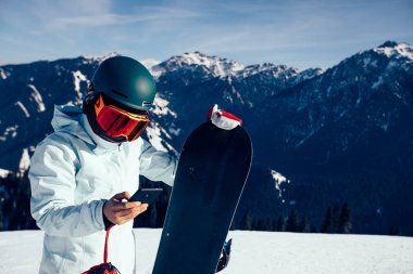bir snowboard kış dağın tepesinde Smartphone kullanarak