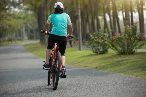 woman cyclist riding bike on forest trail