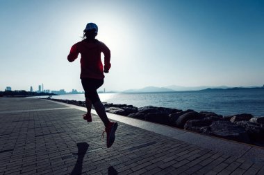 Sportif genç fitness kadın gündoğumu sahil üzerinde çalışan