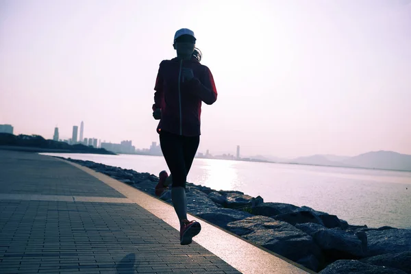 运动的年轻健身妇女剪影在日出海岸小径上奔跑 — 图库照片