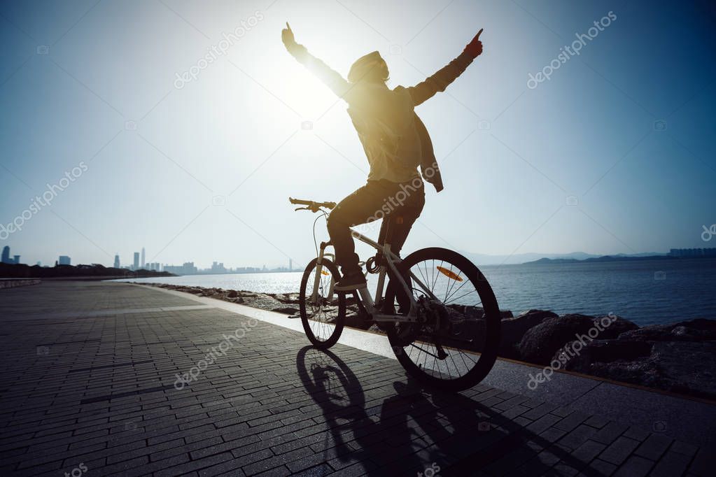 silhouette cyclist riding bike in the sunrise coast road