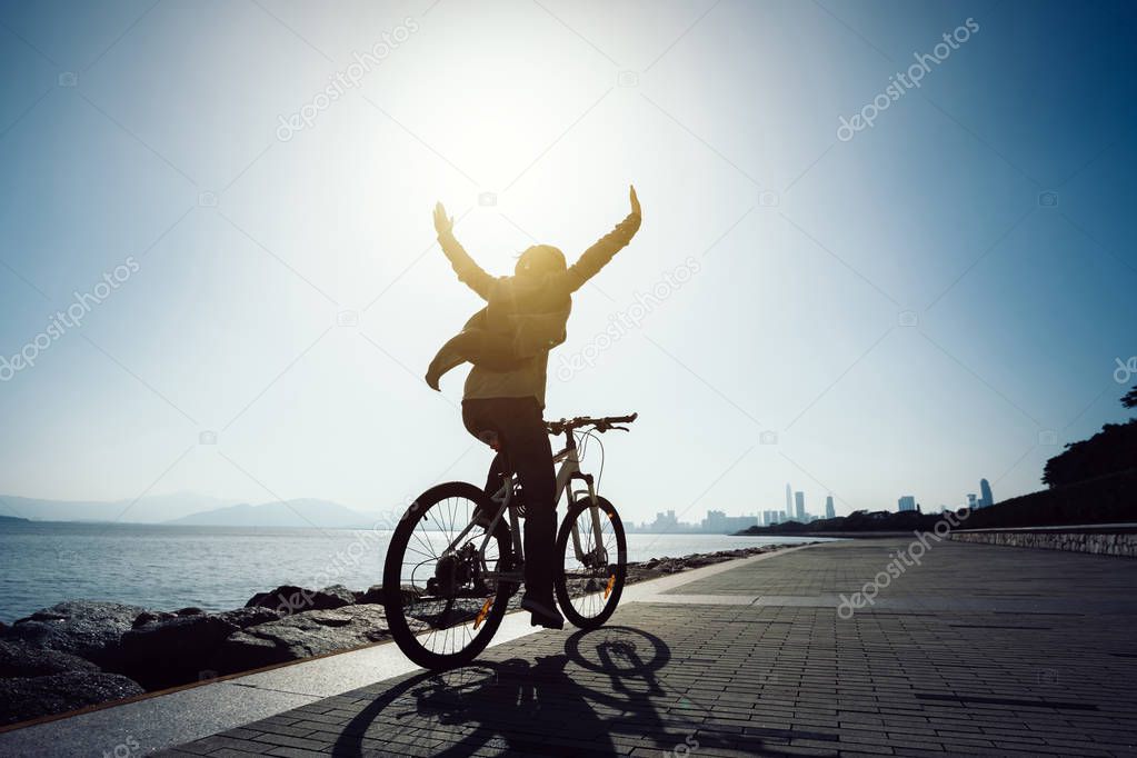 silhouette of happy cyclist riding bike in the sunrise coast 