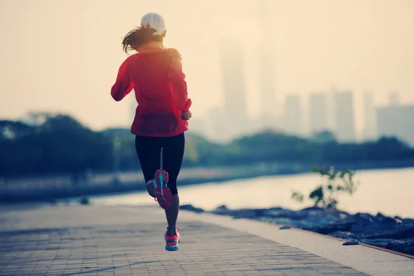 运动的年轻健身妇女剪影在日出海岸小径上奔跑 — 图库照片