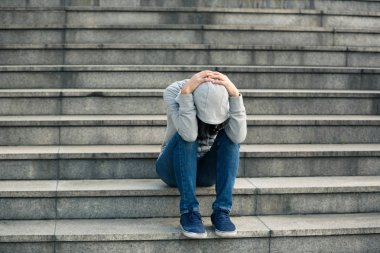 Upset woman sitting alone in city stairs clipart