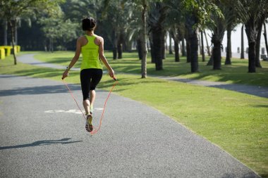 Genç fitness kadın tropikal Park'ta ip atlama