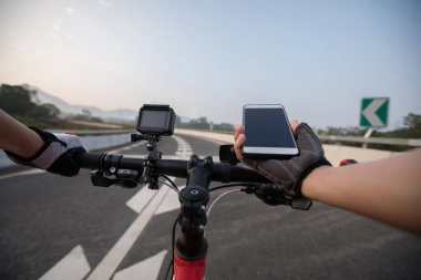 Bisikletçi dağ bisikleti karayolu üzerinde sürme sırasında gezinti için Smartphone kullanarak