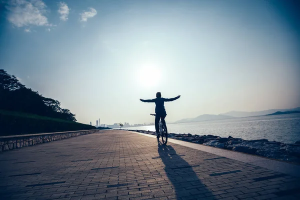 剪影自行车手骑自行车在日出海岸路 — 图库照片