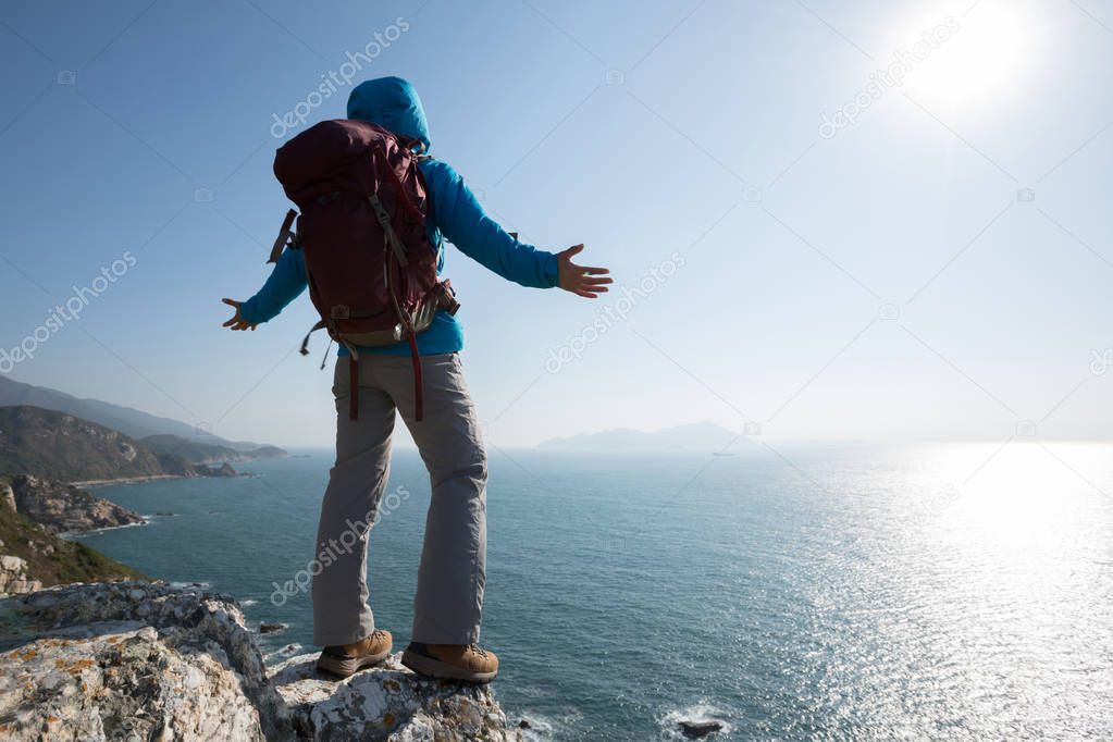  female hiker standing on sunrise seaside mountain  