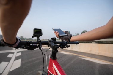 Bisikletçi dağ bisikleti karayolu üzerinde sürme sırasında gezinti için Smartphone kullanarak 