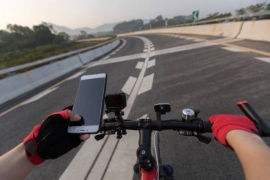 Bisikletçi dağ bisikleti karayolu üzerinde sürme sırasında gezinti için Smartphone kullanarak 