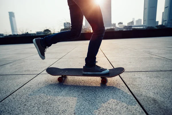 Skateboarder legs skateboarding at sunrise city