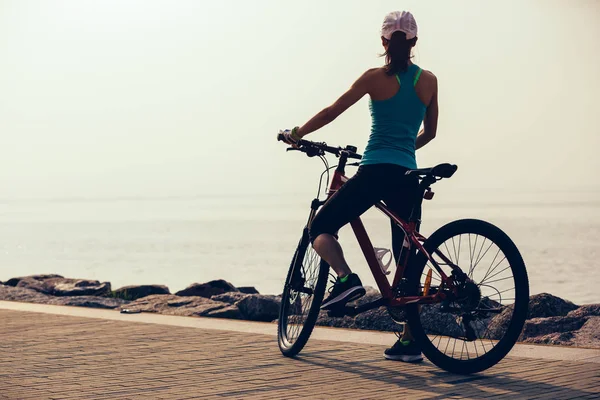 在海滨骑山地自行车的女骑手 — 图库照片