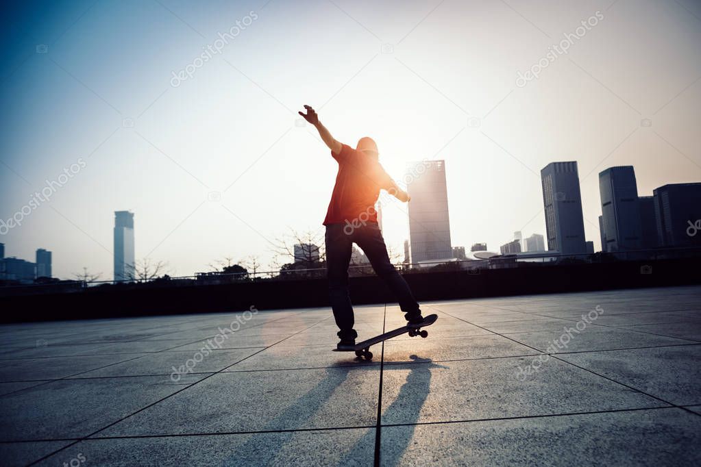 Skateboarder skateboarding on roof of building at sunrise city