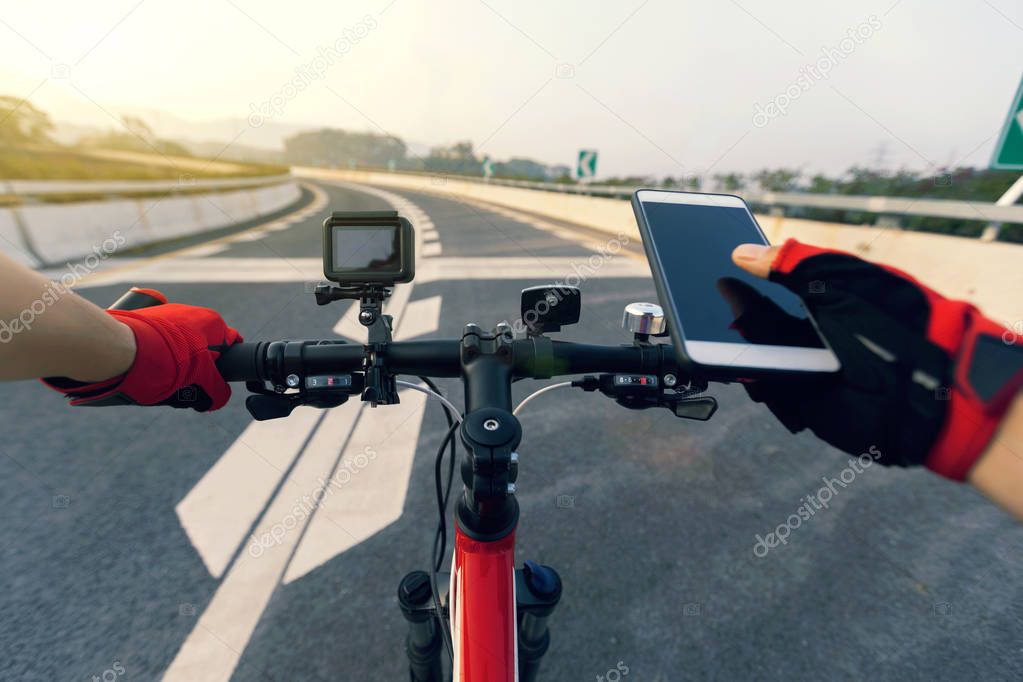 Cyclist using smartphone for navigation while riding mountain bike on highway