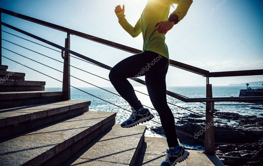 sporty female jogger running upstairs on seaside during sunrise