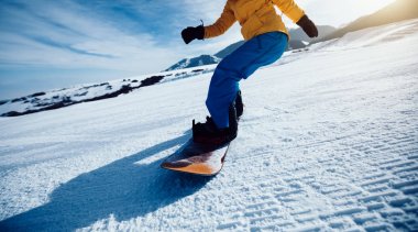 Bir snowboardcu kış dağlarında snowboard yapıyor.