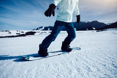 Bir snowboardcu kış dağlarında snowboard yapıyor.