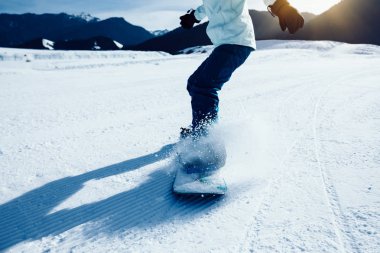 Bir snowboardcu kış dağlarında snowboard yapıyor.