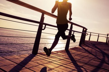 Sahil sahil üzerinde gündoğumu sırasında çalışan sportif kadın runner