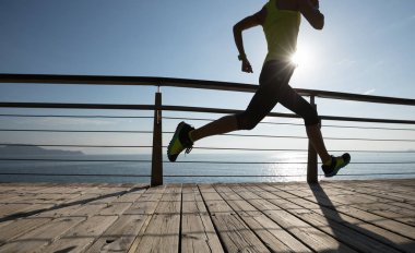 Sahil sahil üzerinde gündoğumu sırasında çalışan sportif kadın runner