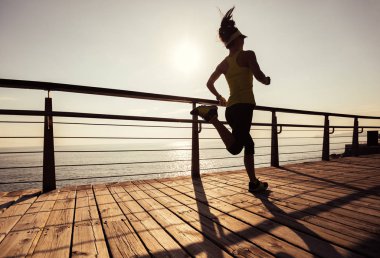 Sahil sahil üzerinde gündoğumu sırasında çalışan sportif kadın runner