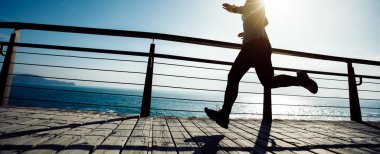 Sahil sahil üzerinde gündoğumu sırasında çalışan sportif kadın runner