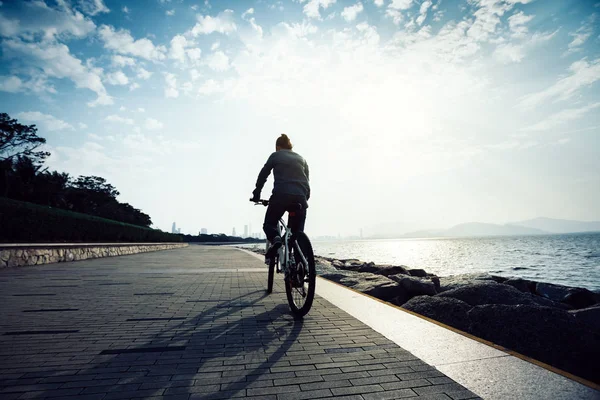 Bisikletçi Gün Doğumunda Sahil Yolunda Bisiklet Sürüyor — Stok fotoğraf