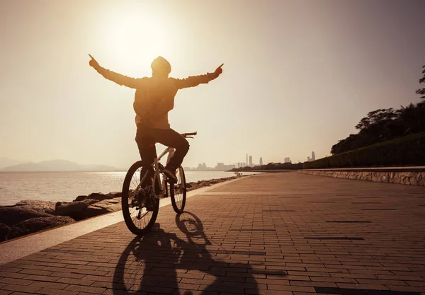 silhouette of cyclist riding bike in the sunrise coast road