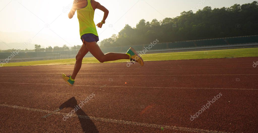 Fitness sportswoman running on sunrise track