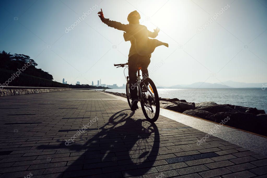 silhouette of cyclist riding bike in the sunrise coast road