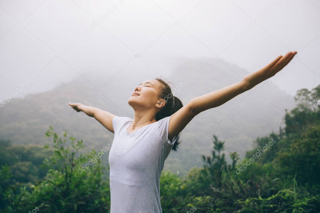 Happy woman with outstretched arms enjoying the view on morning mountain valley