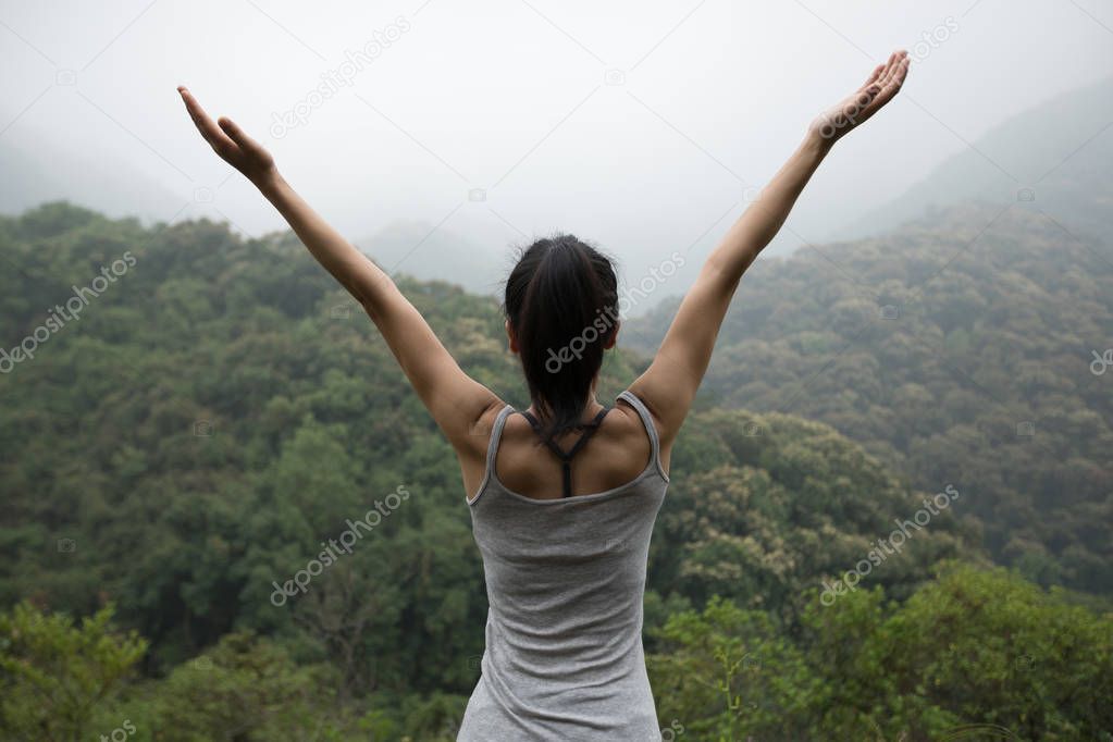 Happy woman with outstretched arms enjoying the view on morning mountain valley