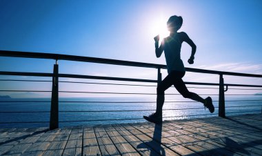 Güneş doğarken sahil kenarında koşan sportif fitness kadın koşucusu