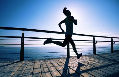 Güneş doğarken sahil kenarında koşan sportif fitness kadın koşucusu