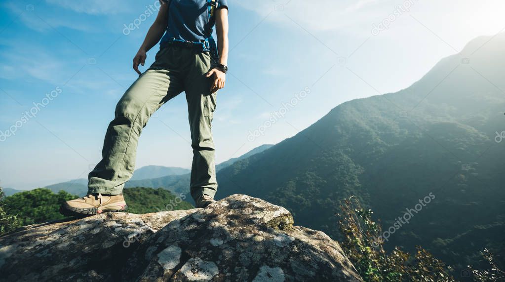 successful hiker standing on sunrise mountain top cliff edge
