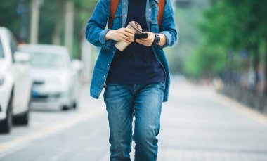 Elinde kahve fincanı ile yürüyüş ve şehir sokak cep telefonu kullanarak