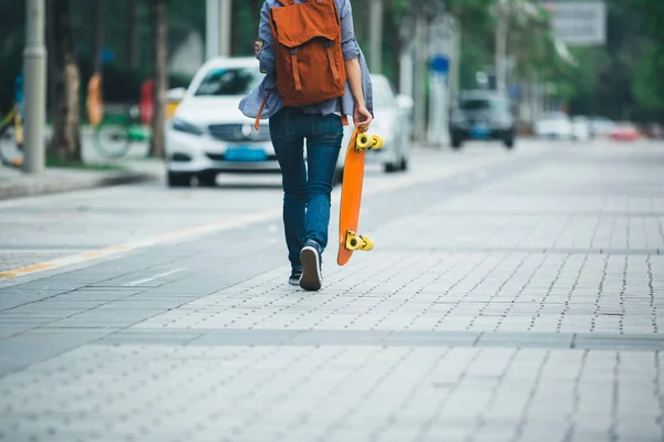 街の通りに手でスケート ボードと一緒に歩いている女性 — ストック写真